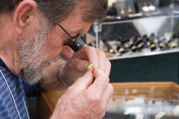 An appraiser inspects a gold ring for purity markings.